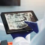 HandsDentistAndTabletScreenForXRayToothDiagnosis