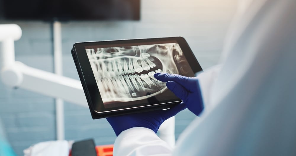 HandsDentistAndTabletScreenForXRayToothDiagnosis