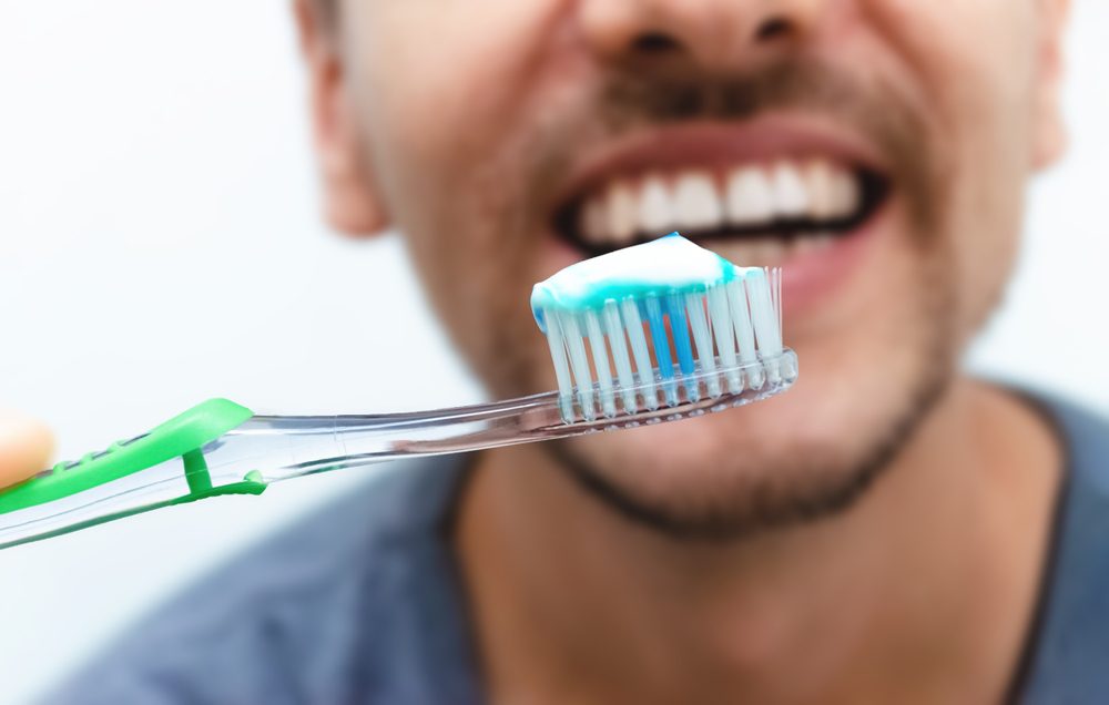 ToothbrushWithToothpasteInClose-upWithSmileOfYoungMan